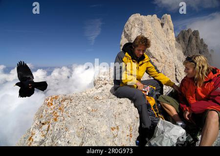 Ein Paar, das sich auf dem Berggipfel erholt, eine Wandertour in der Rosengarten Bergkette, Santnerpass, in der Nähe von Pozza di Fassa, Dolomiten, Südtirol, Stockfoto