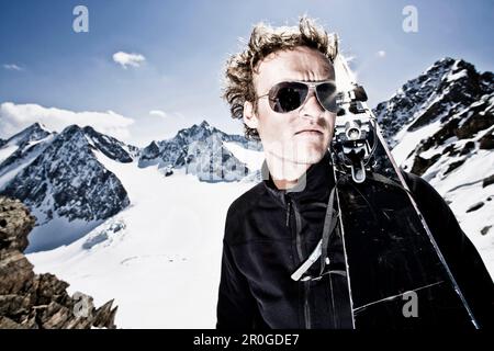 Junger Mann mit Telemark-Skiern auf der Schulter vor der östlichen Seespitze, der Westlichen Seespitze und der Ruderhofspitze, der Wildgratscharte, der Stubaier Alpen, T. Stockfoto