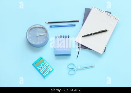 Kalender, Taschenrechner, Wecker und Schreibwaren auf blauem Hintergrund Stockfoto