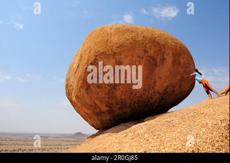 Eine Frau, die roten Granitfelsen von der Platte schubst, Great Spitzkoppe, Namibia Stockfoto