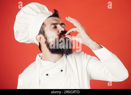 Der Koch zeigt das Schild in Ordnung, Genussgeste probieren. Koch mit Geste für die Genehmigung des Restaurantservice. Professioneller Koch in Uniform mit Schild für Delicious Stockfoto