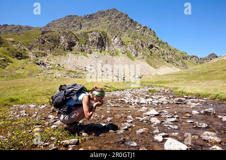 Wanderer, die aus einem Fluss in der Nähe des Sees Lac Roumassot, Ossau Valley, der französischen Pyrenäen, der Pyrenäen-Atlantiques, Aquitanien, Frankreich Stockfoto