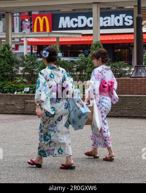 Japanische Frauen in traditionellen Kimonos passieren McDonalds in Tokio. Stockfoto