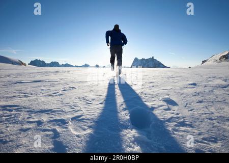 Mann, der über den Gletscher zum Sonnenaufgang fährt, mit Blick auf Les Grandes Jorasses und Dent du Geant, Chamonix Mont Blanc, Frankreich, Europa Stockfoto