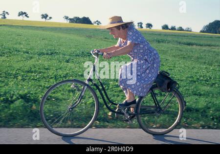 Ältere Frau, die Fahrrad fährt, Oberbayern, Deutschland Stockfoto