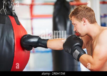 Die Tasche zuschlagen. Ein junger Boxer, der mit einem Boxball im Fitnessstudio trainiert. Stockfoto