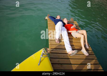 Ein junges Paar liegt entspannt auf einem Steg, Woerthsee, Bayern, Deutschland, Europa Stockfoto