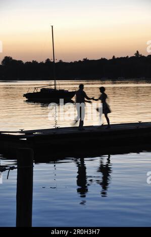 Paar tanzen auf einem Steg am Ammersee bei Sonnenuntergang, Herrsching, Oberbayern, Deutschland, Europa Stockfoto