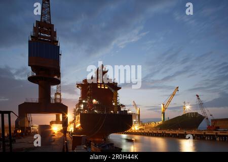Krane und Containerschiffe bei Nacht, Werft Ouhua, Zhoushan, Provinz Zhejiang, China Stockfoto