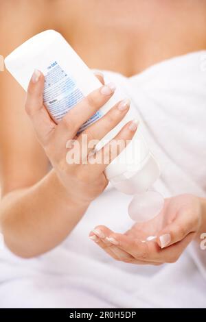 Ich achte darauf, dass meine Haut Feuchtigkeit einschließt. Eine junge Frau, die Körperlotion auf ihre Hand presst. Stockfoto