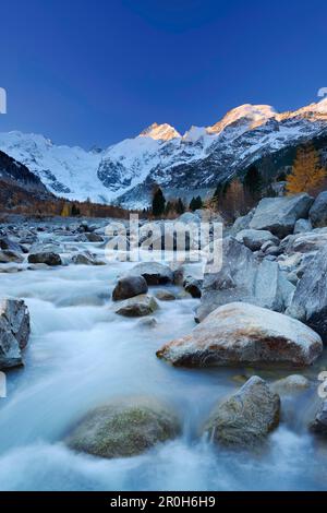 Fluss durch Morteratsch Tal im Morgenlicht mit Bernina Strecke im Hintergrund fließt, Bernina, Engadin, Graubünden, Schweiz Stockfoto