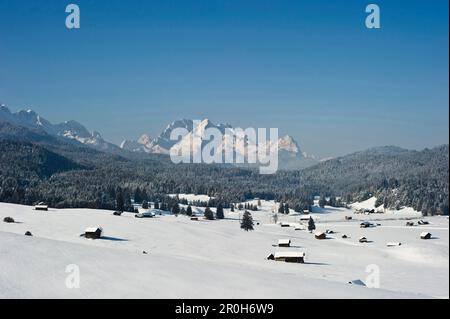 Schneebedeckte Hütten bei Mittenwald, Zugspitze im Hintergrund, Bayern, Deutschland Stockfoto