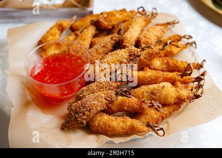 Köstliche frittierte Meeresfrüchte und Hähnchen auf Spießen serviert mit süßer Chilisauce, perfekt für ein Fast-Food-Gericht. Stockfoto