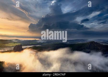 Beeindruckender Gewitter über dem sächsischen Schweizer Nationalpark mit dem Falkenstein in der Abendsonne und Nebel in den Tälern, Sachsen, Deutschland Stockfoto