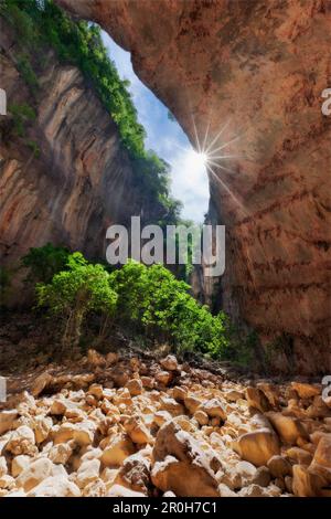 Blick von der Cueva de la Ermita mit Sonnenstrahlen am Grund des tiefen Canyons Gargante Verde in Südspanien, Sierra de Grazalema, Andalusien, Spai Stockfoto