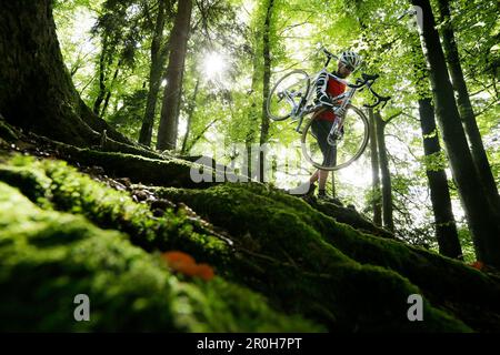 Mann Cyclocross auf Tournee im Herbst, mit dem Fahrrad auf der Schulter, Oberambach, Munsing, Bayern, Deutschland Stockfoto