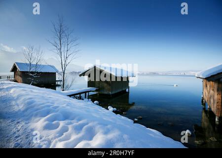 Verschneite Bootshäuser am See Kochel, Oberbayern, Deutschland Stockfoto