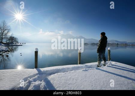 Mann auf Schnee bedeckten Steg am See Kochel, Oberbayern, Deutschland Stockfoto