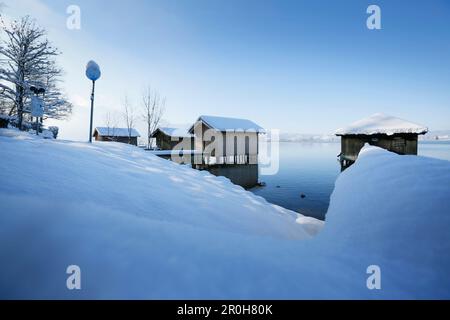 Verschneite Bootshäuser am See Kochel, Oberbayern, Deutschland Stockfoto