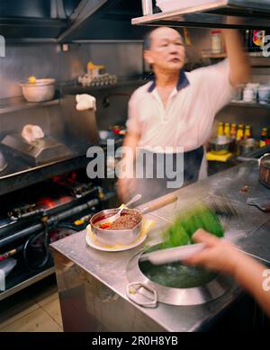 Singapur, Asien, Küchenchef im Newton Food Court Küche arbeiten Stockfoto