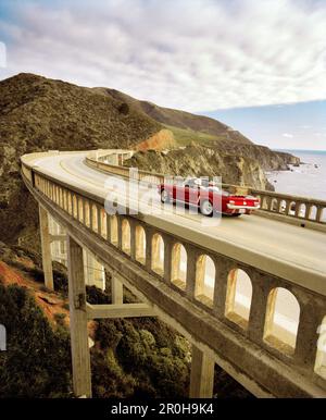 USA, Kalifornien, Big Sur, Paar in einem 1965 Mustang auf einem Roadtrip, Bixby Bridge, Highway 1 Stockfoto