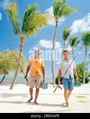 USA, Florida, zwei Männer zu Fuß am Strand mit Angelruten und Boxen angehen, Islamorada Stockfoto