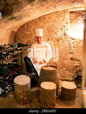 Frankreich, Auxerre, Yonne, Burgund, Portrait von Chef Jean-Luc Barnabet im Weinkeller sitzen an seinem Restaurant Jean-Luc Barnabet Stockfoto