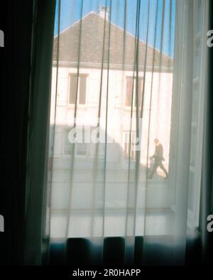 FRANKREICH, Burgund, ein Mann, der auf der Straße durch ein Fenster mit Vorhängen läuft, Chablis Stockfoto