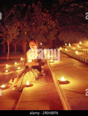Indien, Jaipur, Frau sitzt mit angezündeten Kerzen auf Schritte, Oberoi Rajvilas Hotel Stockfoto