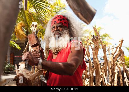 MAURITIUS, ein einheimischer Holzschnitzer arbeitet auf einer Schnitzerei von der Waterfront in Port Louis Stockfoto