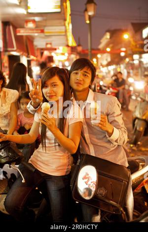 VIETNAM, Hanoi, ein süßes junges Paar sitzt auf ihrem Moped Eis essen an einem heißen Sommerabend in der Innenstadt von Hanoi Stockfoto