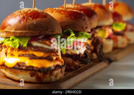 Viele verschiedene Burger mit Zutaten auf einer Holzplatte Stockfoto