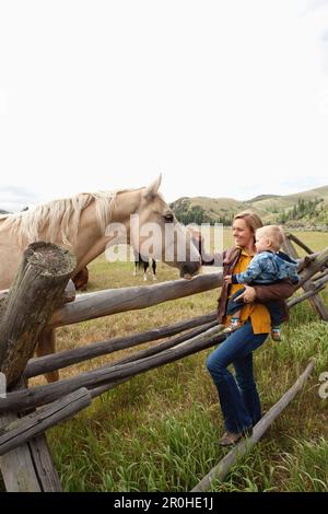 USA, Wyoming, Encampment, eine Frau und ihr Sohn streicheln ein Pferd auf der Abara Ranch Stockfoto