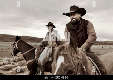 USA, Wyoming, Encampment, Cowboys auf dem Pferderücken bereiten sich darauf vor, Rinder für ein Branding zu sammeln, Big Creek Ranch (B&W) Stockfoto