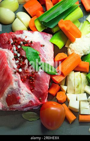 Rohes Schweinefleisch, umgeben von Suppengemüse und Gewürzen Stockfoto