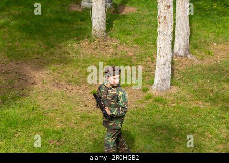 Ein Junge in Tarnung, der Laser-Tag auf einem speziellen Waldspielplatz spielt. Laser Tag ist ein militärisches taktisches Kommandospiel mit sicheren Laserwaffen und SE Stockfoto