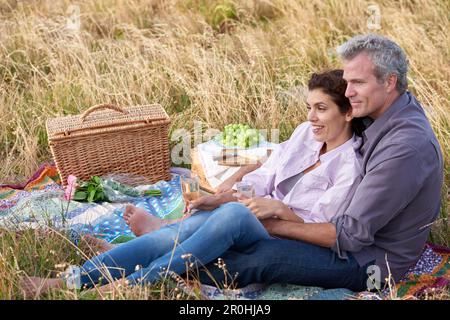 Nichts Romantischeres als ein Picknick. Ein liebevolles reifes Paar genießt ein intimes Picknick zusammen in einem malerischen Feld. Stockfoto