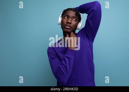 Gut gepflegter, dunkelhaariger junger europäischer Brünetter mit Dreadlocks und kabellosen Kopfhörern Stockfoto