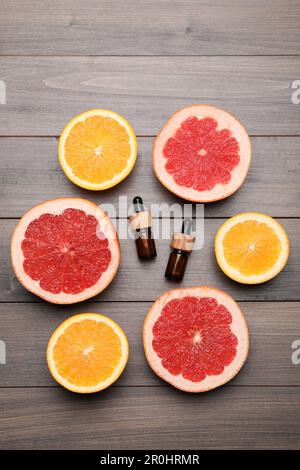 Flaschen mit ätherischen Zitrusölen und frischem Obst auf Holztisch, flach liegend Stockfoto