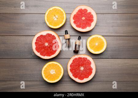Flaschen mit ätherischen Zitrusölen und frischem Obst auf Holztisch, flach liegend Stockfoto