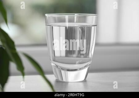 Glas reines Wasser auf einem Holztisch vor verschwommenem Hintergrund Stockfoto