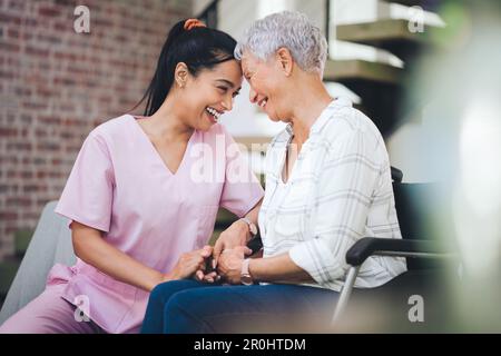 Romantisieren Sie Ihre Jugend, sie ist wirklich flüchtig. Eine junge Krankenschwester, die sich um eine ältere Frau im Rollstuhl kümmert. Stockfoto