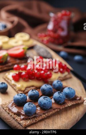 Frisches knuspriges Roggen-Knusperbrot mit verschiedenen Belägen auf Holzbrett, Nahaufnahme Stockfoto