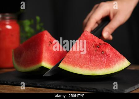 Frau schneidet köstliche Wassermelone auf Schieferbrett, Nahaufnahme Stockfoto