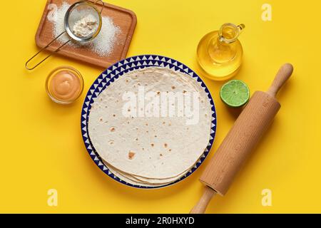 Platte mit dünnem Lavasch und Zutaten auf gelbem Hintergrund Stockfoto