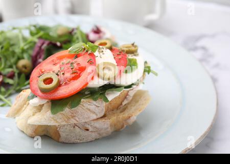 Leckere Bruschetta mit Tomaten, Oliven und Mozzarella, serviert auf dem Teller, vor der Tür Stockfoto