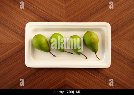 Vier Birnen in einem Gericht auf einem Tisch, Obst, Essen Stockfoto