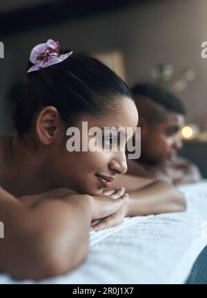 Ausfallzeiten sind für Paare von entscheidender Bedeutung, um gemeinsam Spaß zu haben. Eine junge Frau, die mit ihrem Partner in einem Spa auf einem Massagebett liegt. Stockfoto
