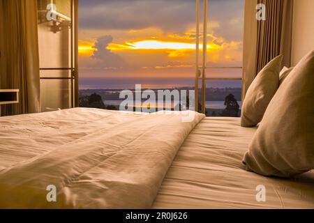 Minimalistisches Schlafzimmer mit Blick auf das Meer bei Sonnenuntergang. Stockfoto