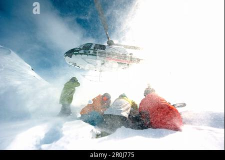 Skifahrer, die einen Helikopter beobachten, Chugach Powder Guides, Girdwood, Alaska, USA Stockfoto